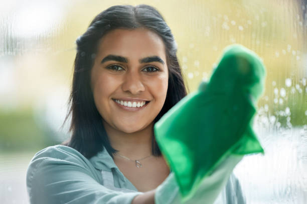 Lady cleaning window with green cloth