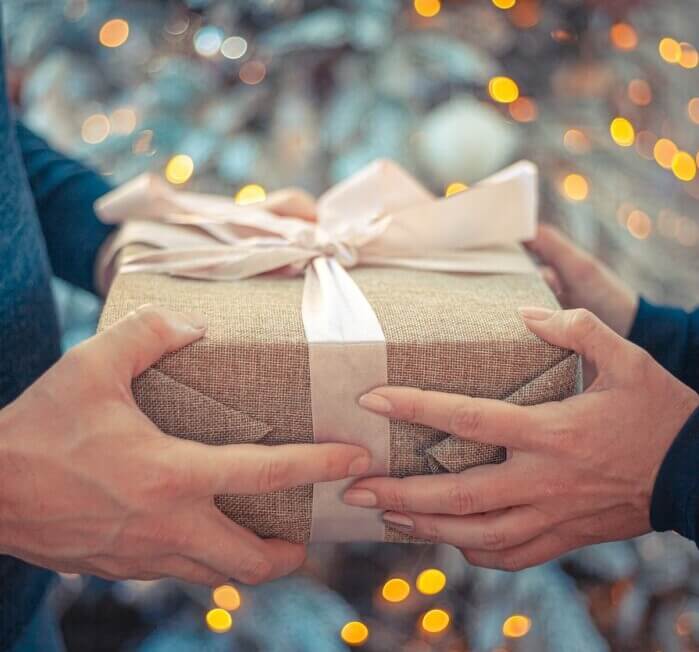 Two peope holding a gift with eco-friendly wrap and ribbon