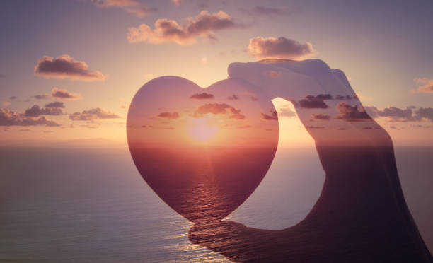 Hand holding a heart in sunset