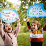Happy kids holding placards for environmental conservation at the park.