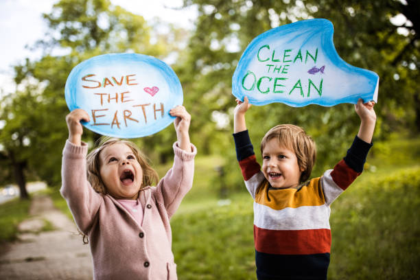 2 young children holding eco-friendly message cutouts for environmental conservation