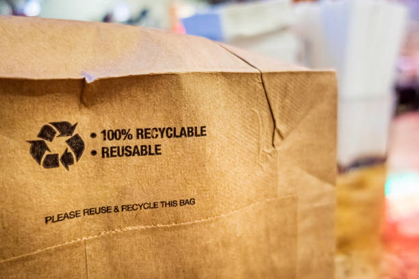 Brown paper bag that is 100% recyclable and reusable on a counter. A printed plea for user to recycle and reuse this bag as a form of packaging.