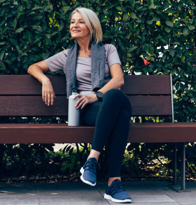 Lady sitting on a park bench holding a stainless-steel reusable bottle