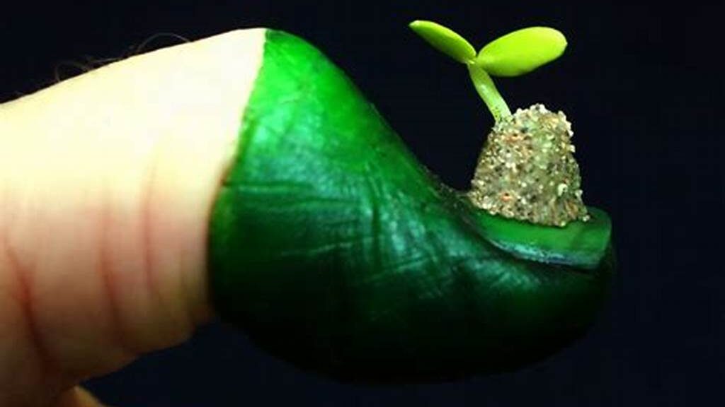 Thumb half painted green with miniature seedling sitting on nail